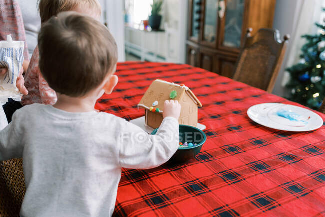 Little boy and sister decorating gingerbread house with icing — Stock Photo