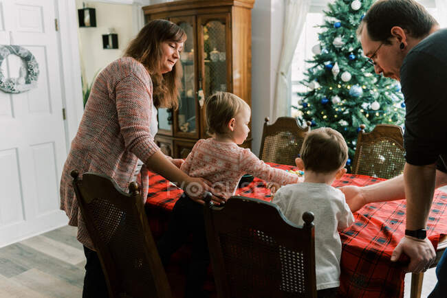 Familie mit kleinen Kindern dekoriert im Dezember ein Lebkuchenhaus — Stockfoto