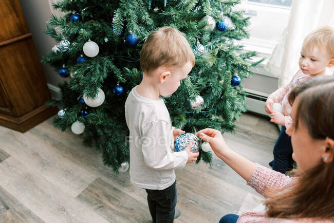 A mother and her children decorating their christmas tree together — Stock Photo