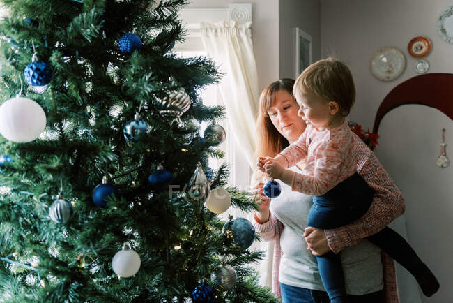 Family with little children decorating a christmas tree in December — Stock Photo