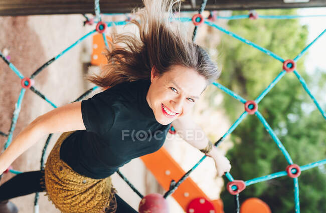 Donna sorridente che tiene una mano ad un'altalena a forma di rete — Foto stock