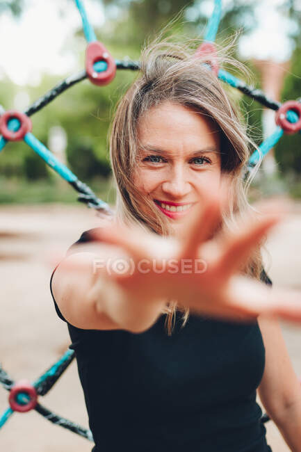 Sorridente donna cercando di catturare la fotocamera con la mano — Foto stock