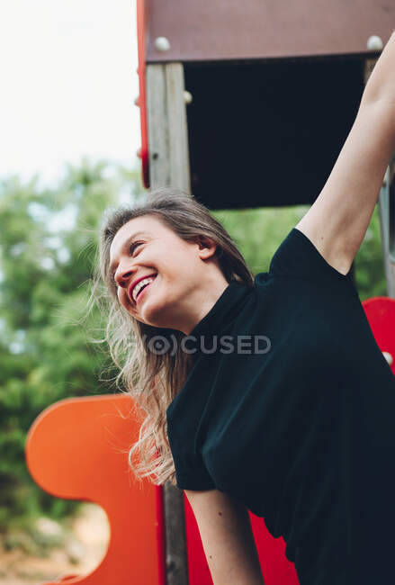 Perfil tiro de uma mulher sorridente escalando em um balanço — Fotografia de Stock