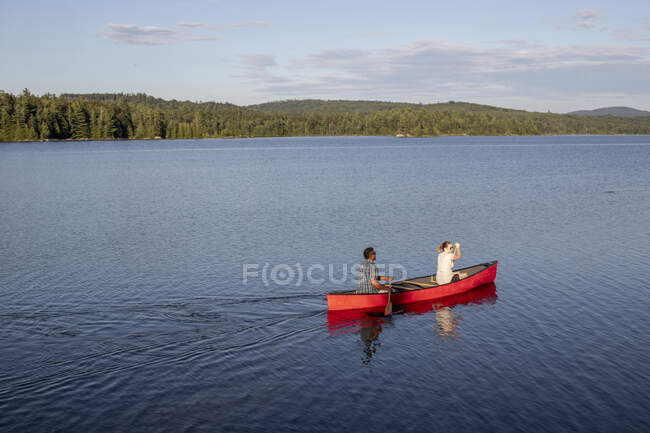 Homem africano e mulher branca em canoa vermelha no lago em Maine Woods — Fotografia de Stock