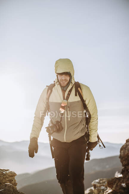 Mann mit Kapuze und Kaltwetterjacke und Kameraausrüstung wandert im Winter. — Stockfoto