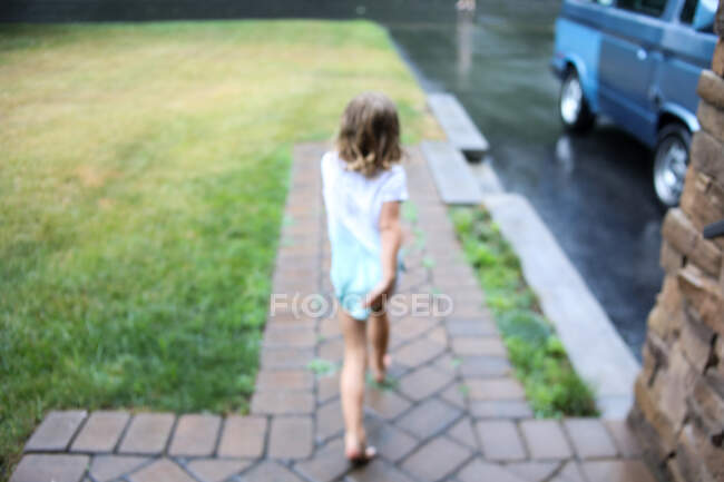 Imagen borrosa de niña corriendo bajo la lluvia en primavera - foto de stock