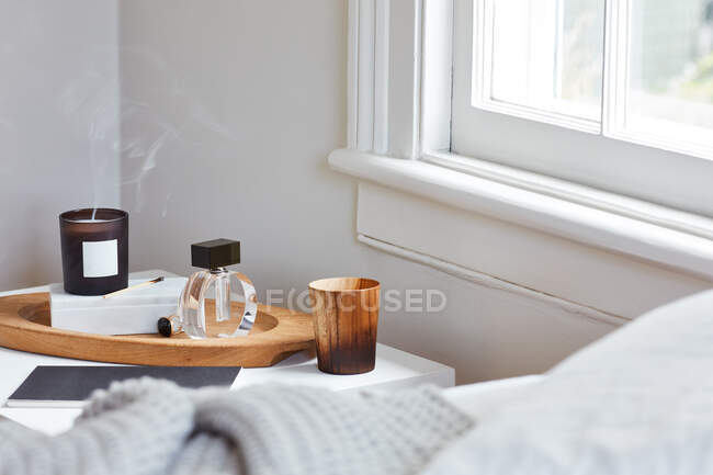 Scented candle at bedside table with perfume — Stock Photo