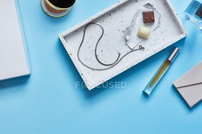 Chocolates, collar, perfume en la superficie turquesa - foto de stock