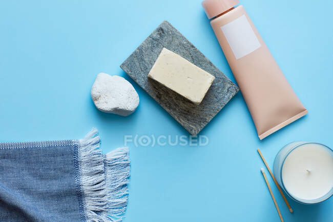 Jabón, crema, vela sobre superficie turquesa - foto de stock