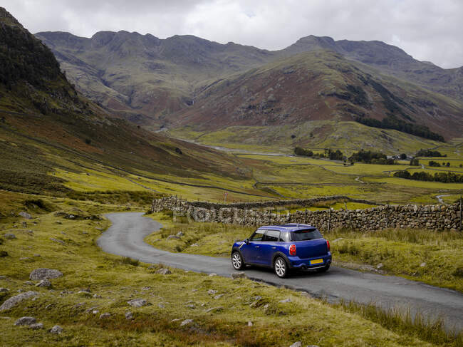 Coche que conduce a través del paso de montaña del Parque Nacional Lake District - foto de stock