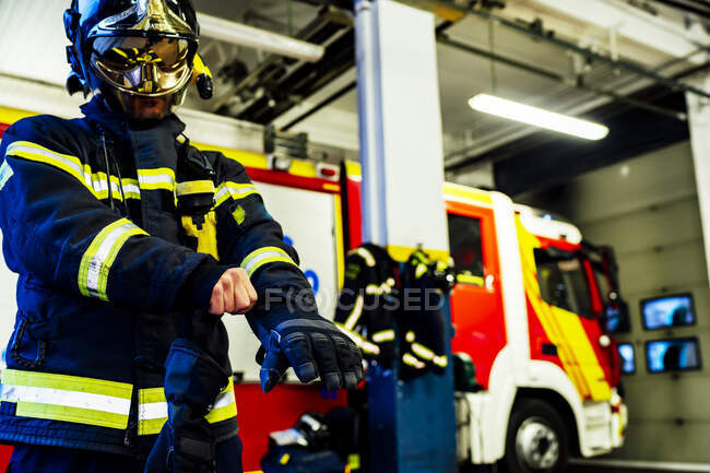 Feuerwehrmann zieht Handschuhe für den Ernstfall an — Stockfoto
