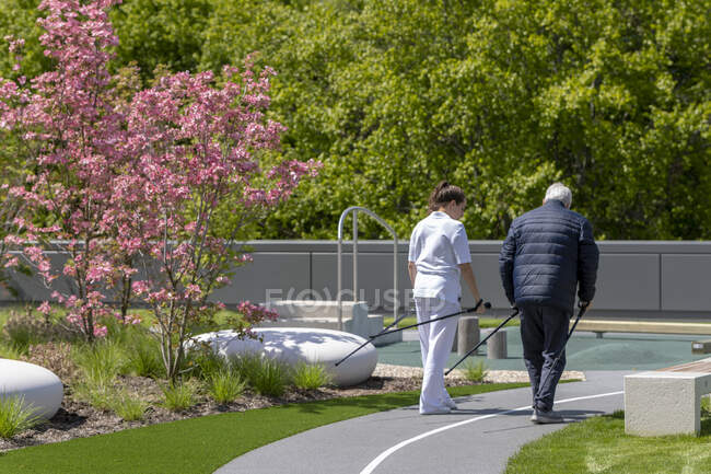 Couple de personnes âgées marchant dans le parc avec des bâtons de randonnée — Photo de stock