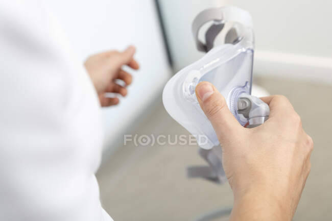 Inyección recortada de médico femenino sosteniendo máscara respiratoria médica - foto de stock