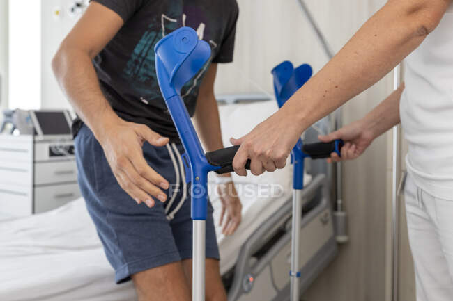 Tiro cortado de homem com muletas no hospital — Fotografia de Stock