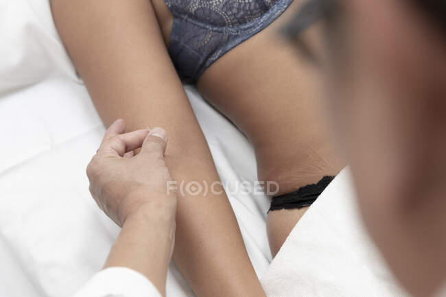 Abgeschnittene Ansicht der Frau auf dem Bett liegend weißer Neurologe zeigt Nadel auf ihre Haut — Stockfoto