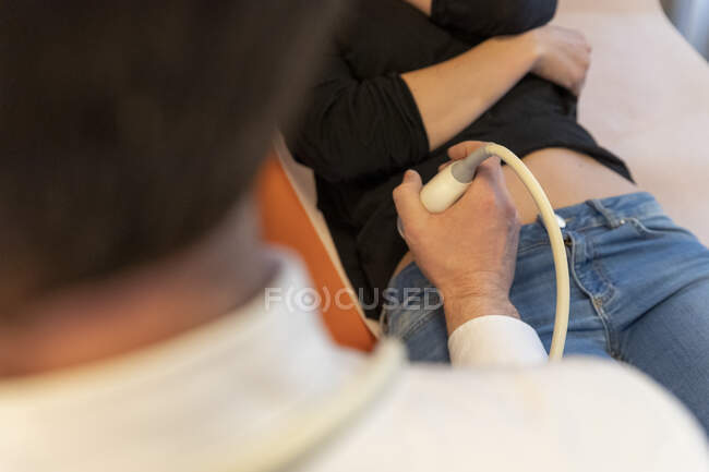 Gros plan du médecin examinant le ventre de la femme enceinte avec échographie — Photo de stock