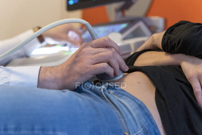 Close-up shot of doctor examining belly of pregnant woman with ultrasound — Stock Photo