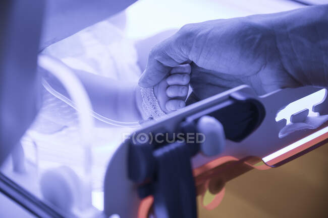 Close-up de médico fêmea examinando bebê recém-nascido sob luz UV — Fotografia de Stock