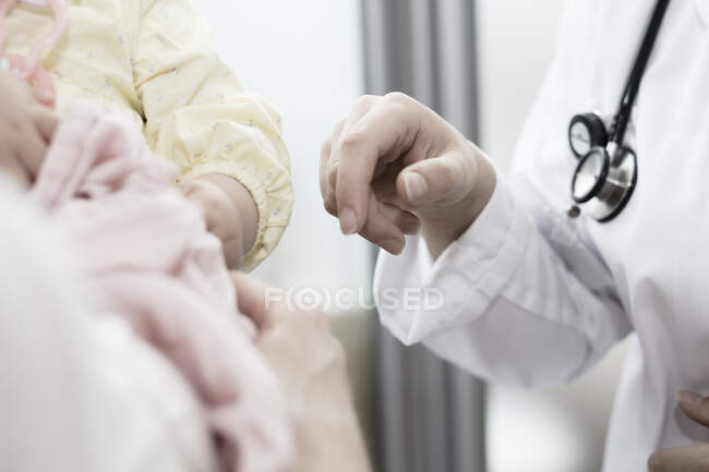 Tiro cortado de mãos de médico pronto para examinar a saúde do bebê recém-nascido — Fotografia de Stock