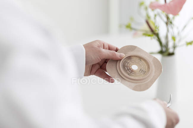 Uomo in possesso di una tazza di tè bianco con uno stetoscopio su uno sfondo leggero — Foto stock