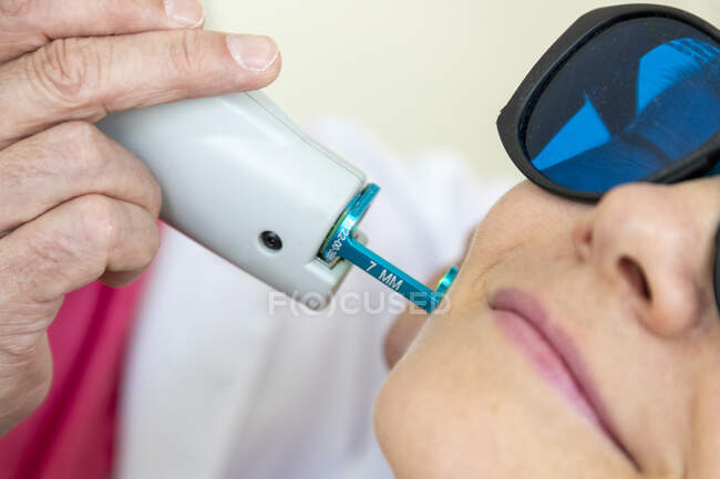 Крупним планом знімок лікаря, що робить лазерну процедуру для пацієнта жінки — стокове фото