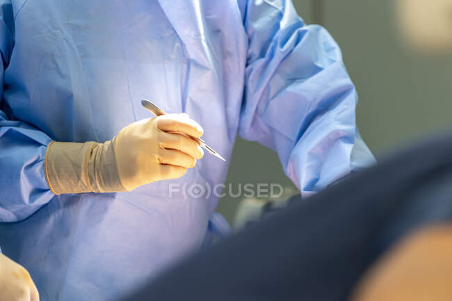 Plano recortado de cirujano sosteniendo bisturí en quirófano - foto de stock