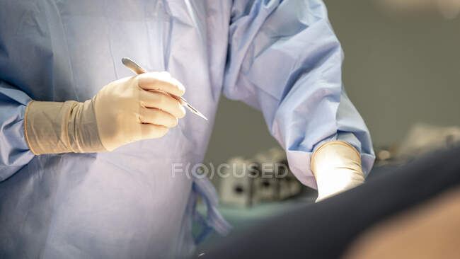 Colpo ritagliato del chirurgo che tiene il bisturi in sala operatoria — Foto stock