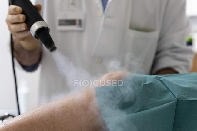 Cropped shot of doctor treats painful knee with cold — Stock Photo