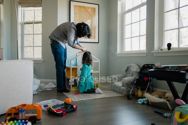 Pai e filha montando casa de bonecas em quarto bagunçado — Fotografia de Stock