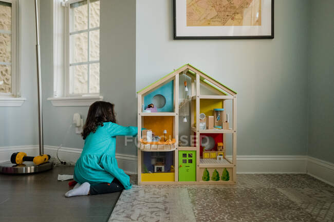 Junges Mädchen spielt mit Puppenhaus im Wohnzimmer — Stockfoto