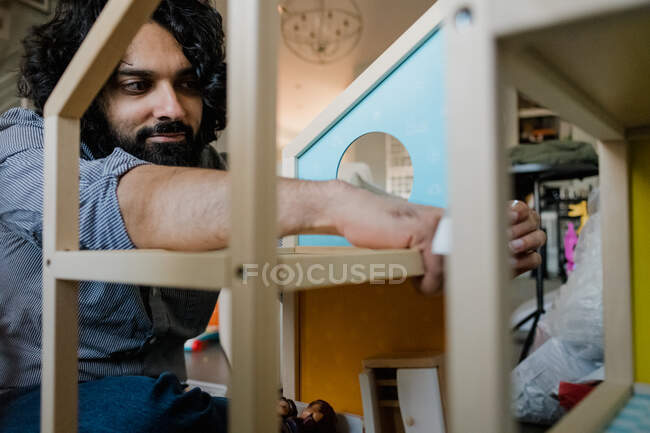 Adult man assembling dollhouse in domestic living room — Stock Photo