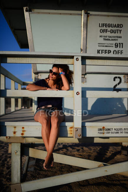 Giovane donna caucasica attraente guardando il mare dalla torre del bagnino nella spiaggia di Malibu, California — Foto stock