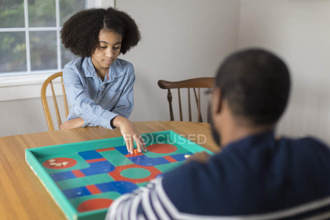 Africana América niña de diez años de edad, jugando juego de mesa con el padre - foto de stock