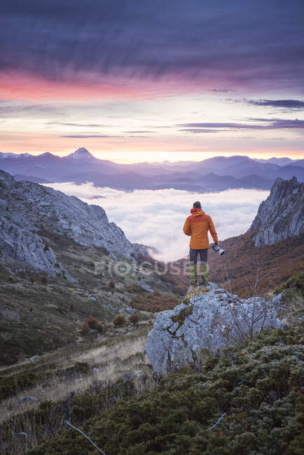 Photographer watching the sunrise over a sea of clouds — Stock Photo