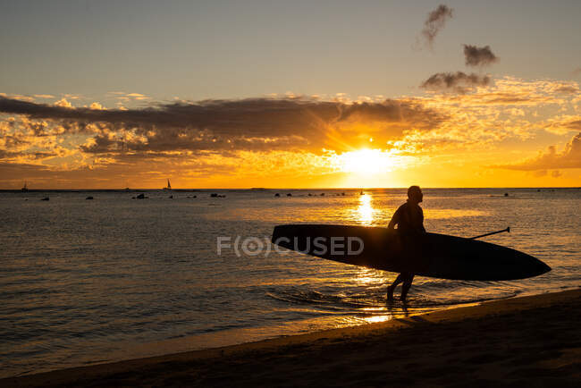 Carrying in stand up paddle board at sunset — Stock Photo
