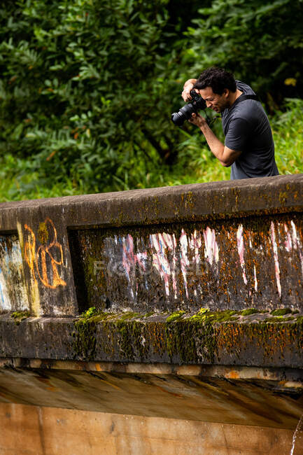 Fit male takes a photo off an old bridge — Stock Photo
