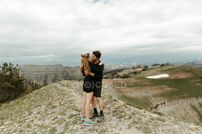 Newly engaged white couple kiss on a mountain top in wyoming — Stock Photo