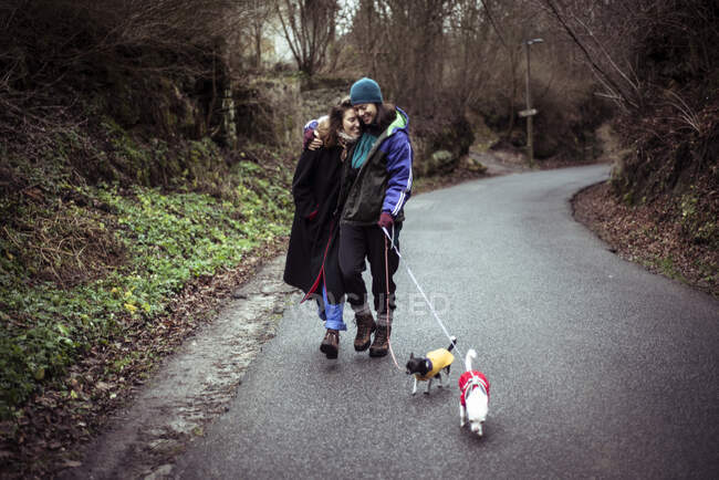 Gay femmina coppia ridere e camminare cani fino campagna strada in ceco inverno — Foto stock
