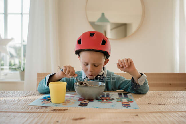 Junge isst Abendessen mit Fahrradhelm auf dem Weg nach draußen — Stockfoto