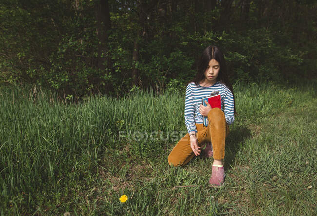 Задумлива дівчина спокійно сидить з книжкою у високій траві у Спрінгтаймі. — стокове фото