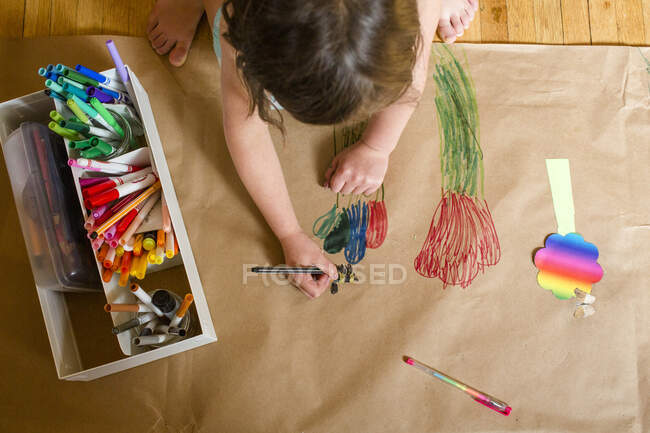 Вид сверху на маленького ребенка, рисующего большую фреску с красочными цветами — стоковое фото