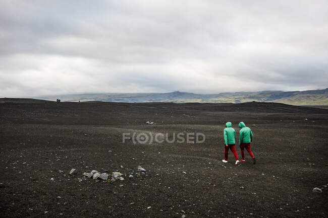 Caminhantes exploram uma praia de areia negra perto de Vik, Islândia. — Fotografia de Stock