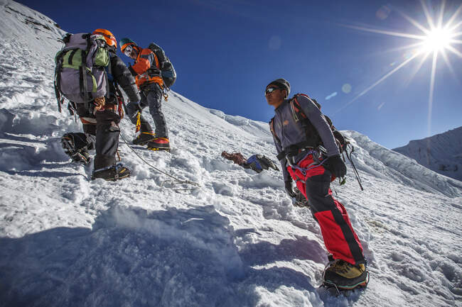 Escaladores subiendo el muro de la cumbre en Island Peak en Nepal. - foto de stock