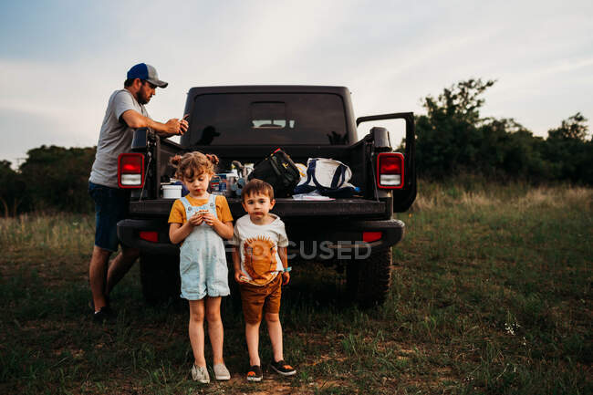 Papà e due bambini che fanno un picnic sul portellone del camion — Foto stock