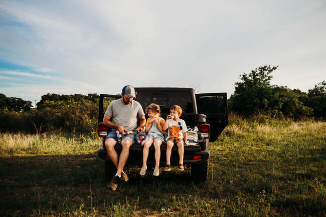 Vater und zwei Kinder picknicken auf der Ladefläche — Stockfoto
