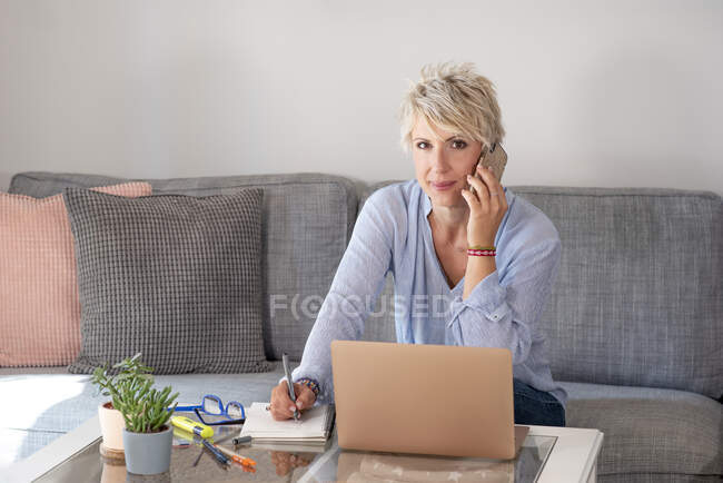 Donna che utilizza laptop sul divano a casa — Foto stock