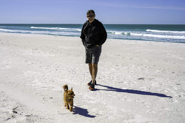 Man and his dog going for a beach walk — Stock Photo