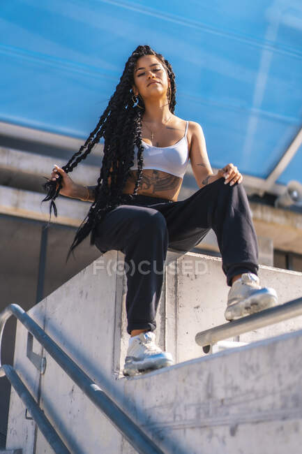 Молодая черная девушка с татуировками, танцовщица-ловушка, сидящая на косе — стоковое фото