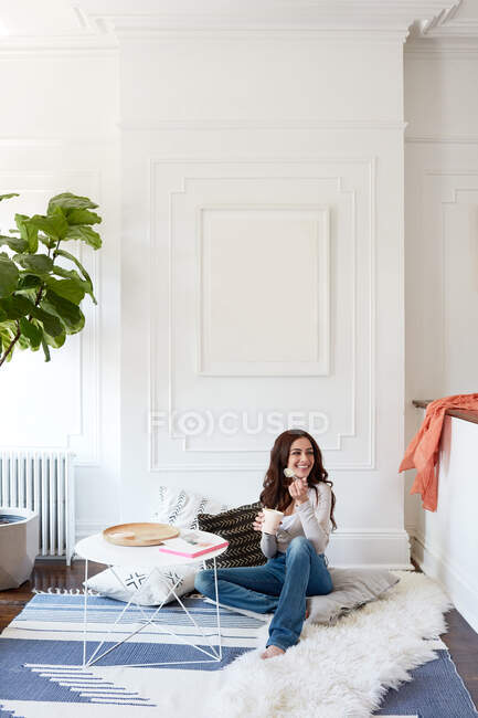 Woman eating ice cream on floor of living room — Stock Photo