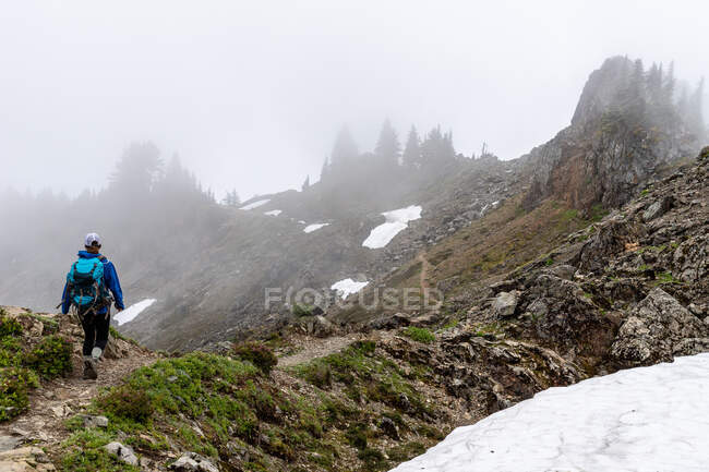 Rear view of backpacker on the trail in mountains — Stock Photo